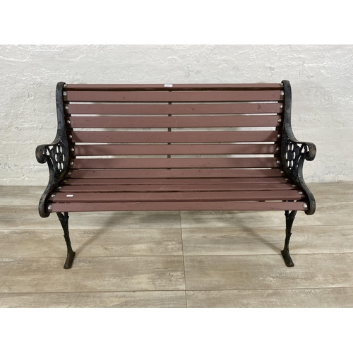 69 - A cast iron and wooden slatted two seater garden bench - approx. 72cm high x 110cm wide x 58cm deep