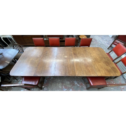 78 - A Victorian oak wind out extending dining table and eleven Cromwellian style oak and red vinyl chair... 