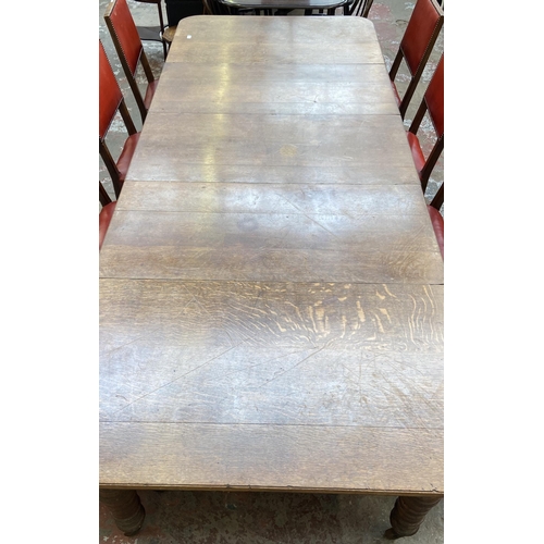 78 - A Victorian oak wind out extending dining table and eleven Cromwellian style oak and red vinyl chair... 