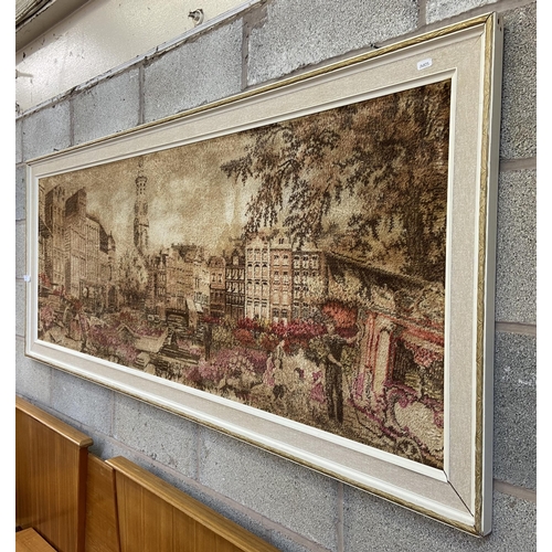 250 - A mid 20th century framed dyed fabric picture of a European scene - approx. 74cm high x 180cm wide