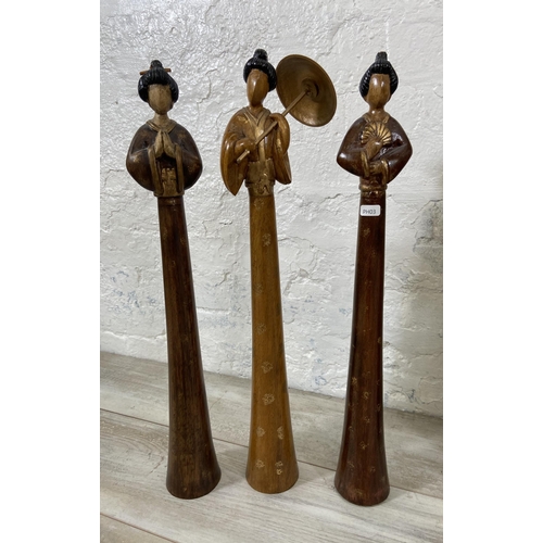 28 - Four Geisha Girl items, three carved wooden figurines - approx. 60cm high and one The Pier hand craf... 