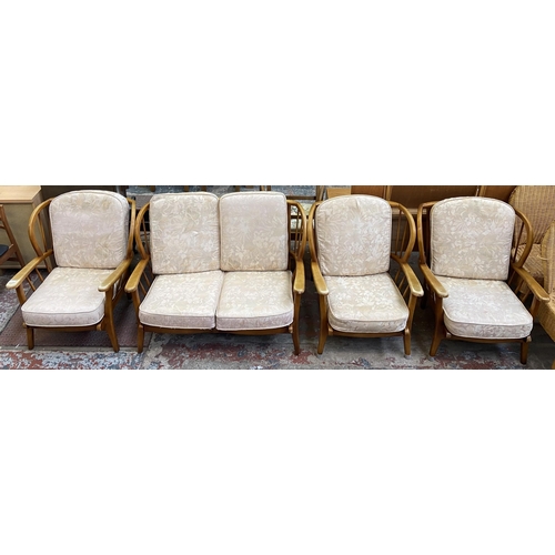 95 - A mid 20th century Ercol style beech four piece lounge suite comprising two seater sofa and three ar... 