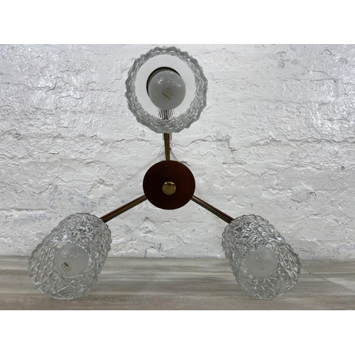 51 - A mid 20th century teak and brass three branch ceiling light fitting with glass shades - approx. 55c... 