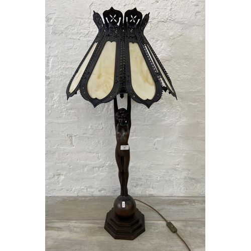 141 - An Art Deco style bronzed metal nude lady figural table lamp with cast metal and stained glass shade... 