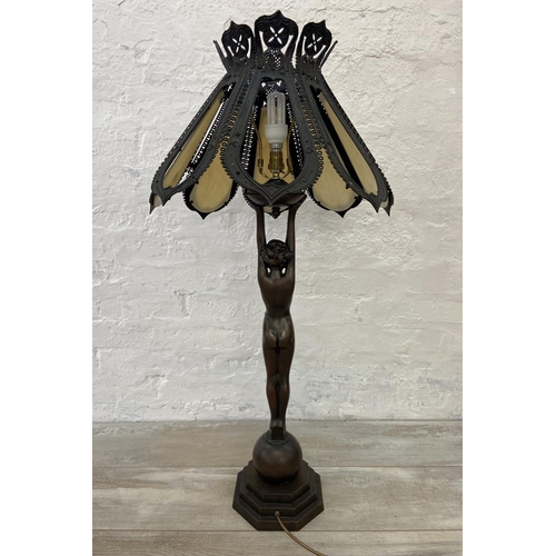 141 - An Art Deco style bronzed metal nude lady figural table lamp with cast metal and stained glass shade... 