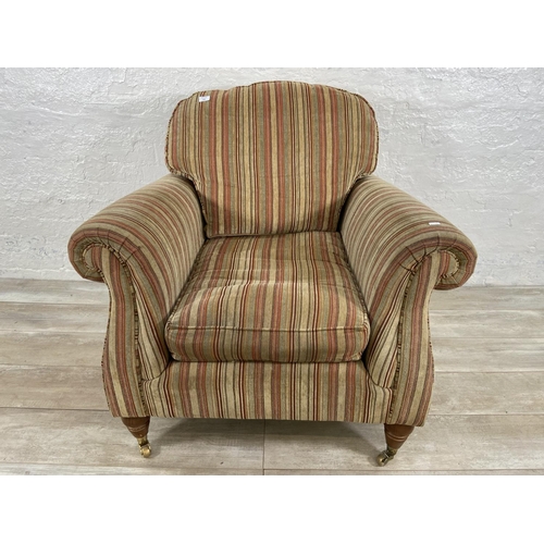 244 - A Parker Knoll fabric upholstered armchair on turned wooden supports and brass castors