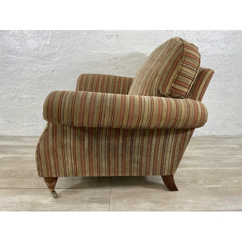 244 - A Parker Knoll fabric upholstered armchair on turned wooden supports and brass castors