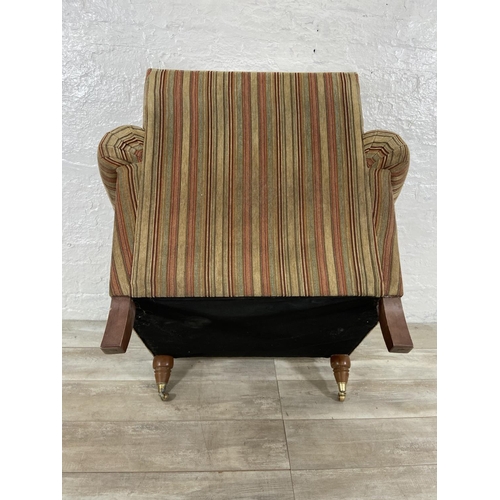 244 - A Parker Knoll fabric upholstered armchair on turned wooden supports and brass castors