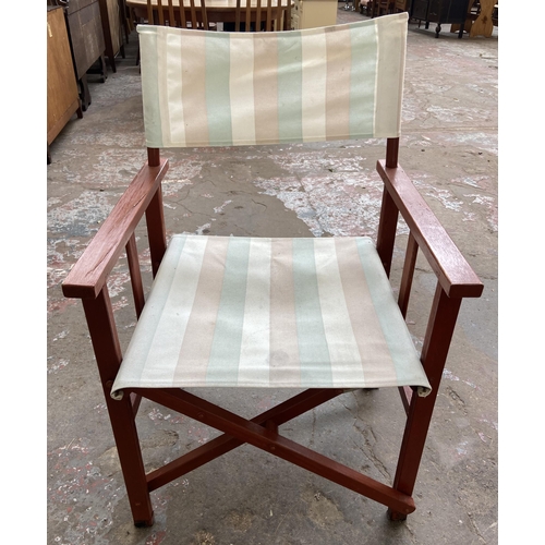 100 - A stained teak three piece patio set comprising circular folding table and two chairs - table approx... 