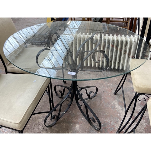 101 - Seven pieces of black painted wrought metal furniture, six dining chairs and one glass top circular ... 