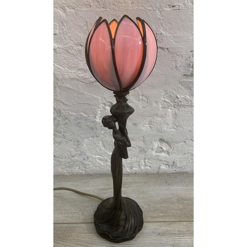 11 - An Art Nouveau style bronzed resin figural table lamp with pink stained and leaded glass tulip shape... 