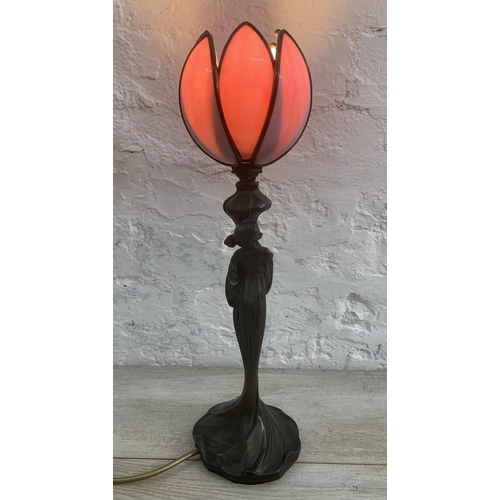 11 - An Art Nouveau style bronzed resin figural table lamp with pink stained and leaded glass tulip shape... 