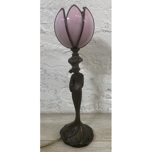 11 - An Art Nouveau style bronzed resin figural table lamp with pink stained and leaded glass tulip shape... 