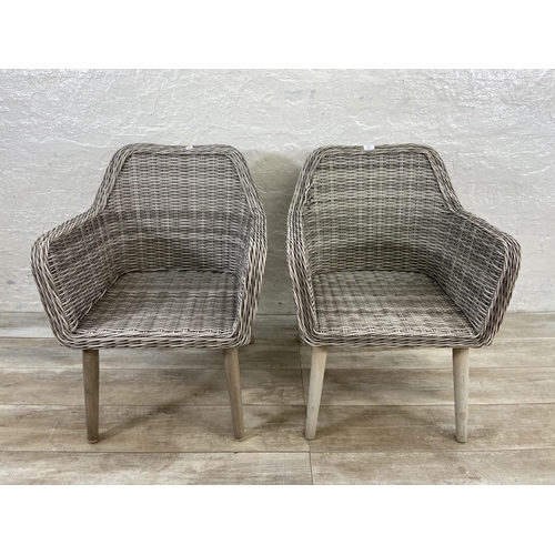 129 - A pair of plastic wicker effect garden armchairs on metal supports