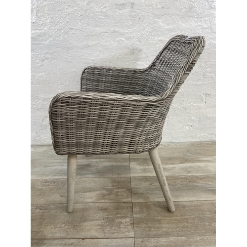 129 - A pair of plastic wicker effect garden armchairs on metal supports