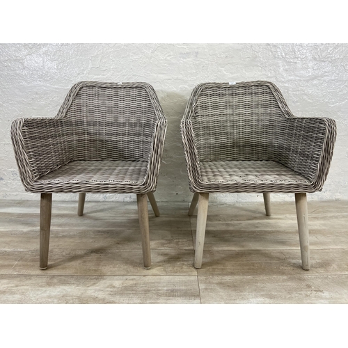 129 - A pair of plastic wicker effect garden armchairs on metal supports