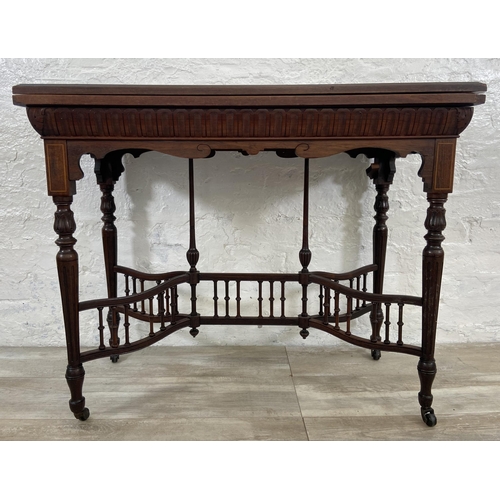 131 - A 19th century inlaid rosewood fold over games table with reeded supports and galleried stretcher - ... 