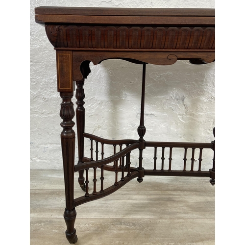 131 - A 19th century inlaid rosewood fold over games table with reeded supports and galleried stretcher - ... 