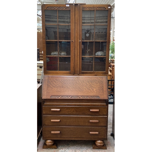 142 - An Art Deco carved oak bureau bookcase on baluster supports - approx. 198cm high x 91cm wide x 42cm ... 