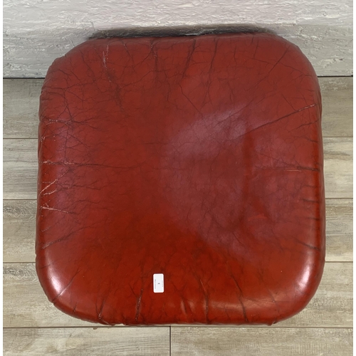 3 - A mid 20th century red leather swivel footstool on castors - approx. 46cm high x 66cm wide