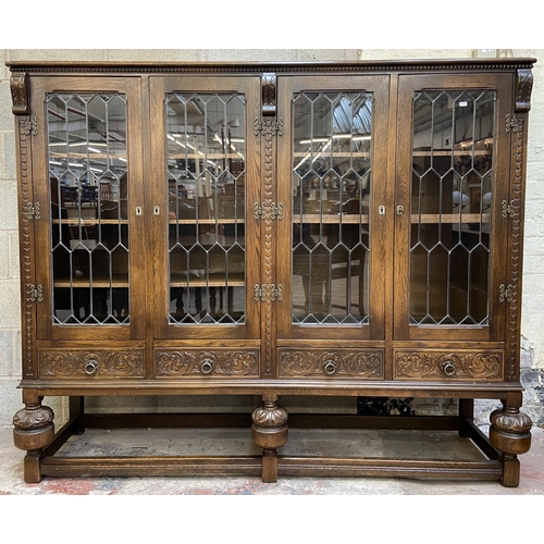 32 - A 17th century style carved oak four door display cabinet on baluster supports - approx. 155cm high ... 