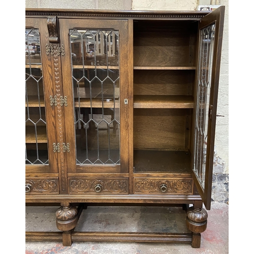 32 - A 17th century style carved oak four door display cabinet on baluster supports - approx. 155cm high ... 