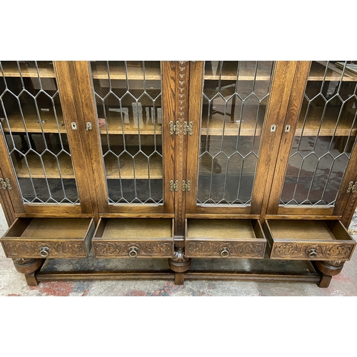 32 - A 17th century style carved oak four door display cabinet on baluster supports - approx. 155cm high ... 