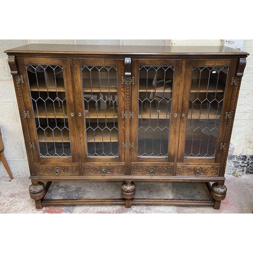 32 - A 17th century style carved oak four door display cabinet on baluster supports - approx. 155cm high ... 