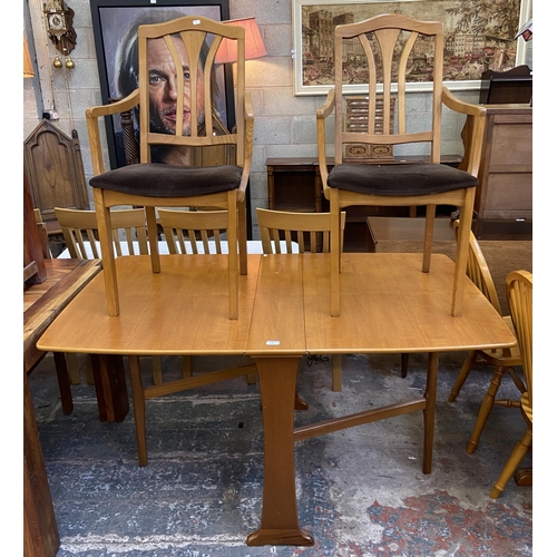 83 - A mid 20th century teak drop leaf gate leg dining table and two Morris of Glasgow elm and brown fabr... 