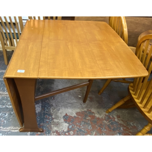 83 - A mid 20th century teak drop leaf gate leg dining table and two Morris of Glasgow elm and brown fabr... 