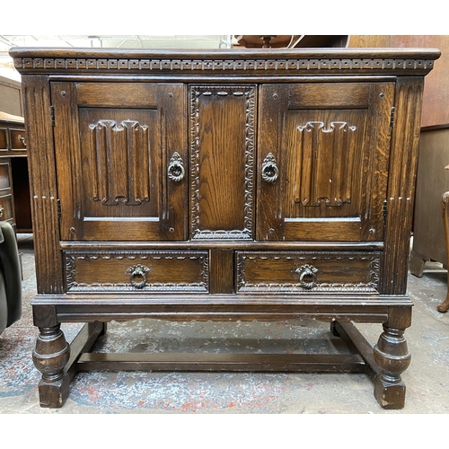 169 - A carved oak two door side cabinet on baluster supports - approx. 85cm high x 92cm wide 43cm deep