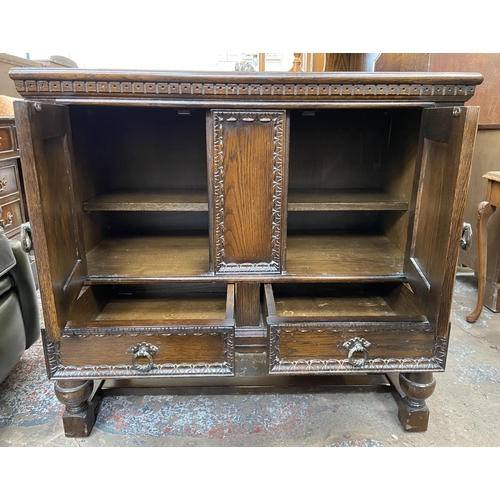 169 - A carved oak two door side cabinet on baluster supports - approx. 85cm high x 92cm wide 43cm deep