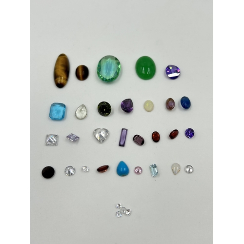 2118 - A collection of gemstones to include tiger's eye, amethyst, blue topaz, garnet etc.