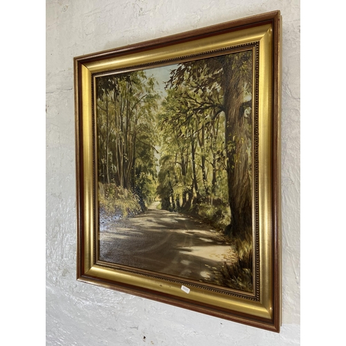 230 - A late 20th century gilt framed oil on canvas of a country lane scene, signed P Robinson and dated 1... 