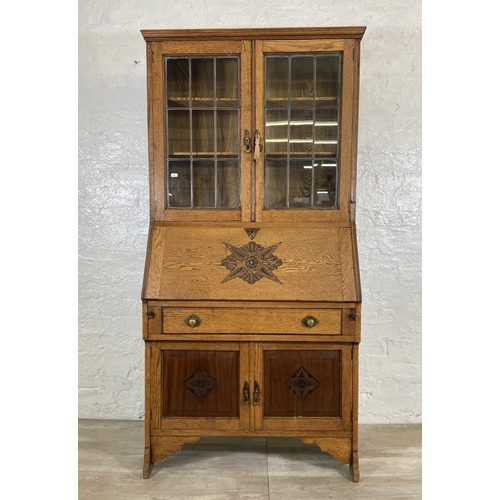 117 - An early 20th century oak bureau bookcase with two lower carved panel doors, one drawer, carved fall... 