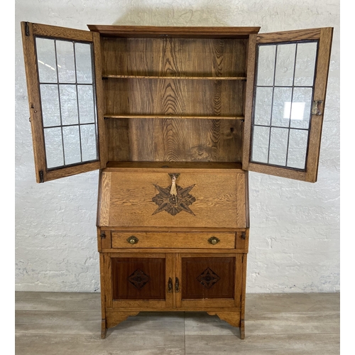 117 - An early 20th century oak bureau bookcase with two lower carved panel doors, one drawer, carved fall... 