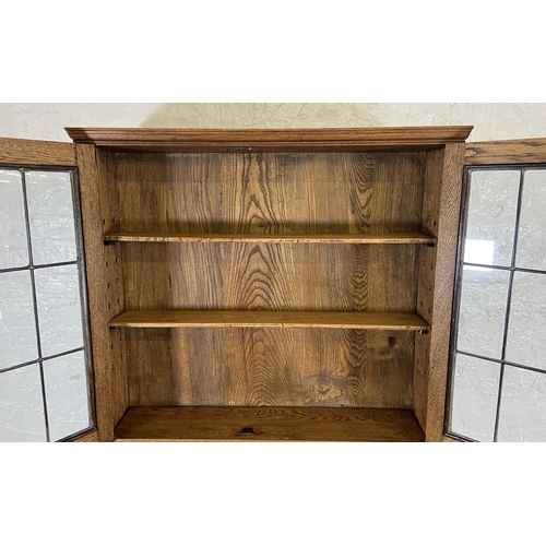 117 - An early 20th century oak bureau bookcase with two lower carved panel doors, one drawer, carved fall... 