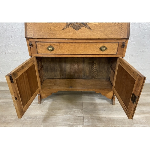 117 - An early 20th century oak bureau bookcase with two lower carved panel doors, one drawer, carved fall... 