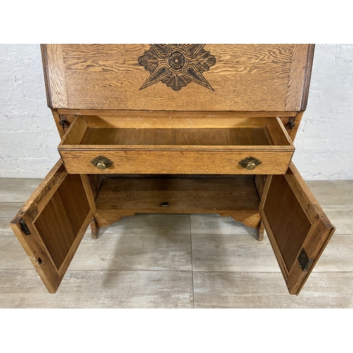 117 - An early 20th century oak bureau bookcase with two lower carved panel doors, one drawer, carved fall... 