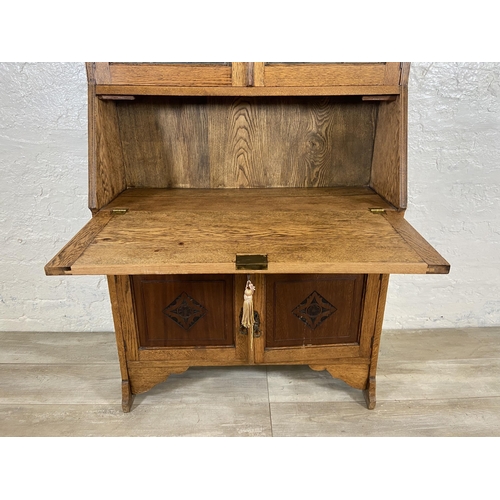 117 - An early 20th century oak bureau bookcase with two lower carved panel doors, one drawer, carved fall... 