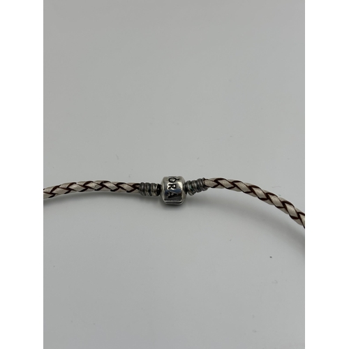 2148 - A Pandora .925 silver and braided leather choker/wrap bracelet with eight .925 silver charms to incl... 