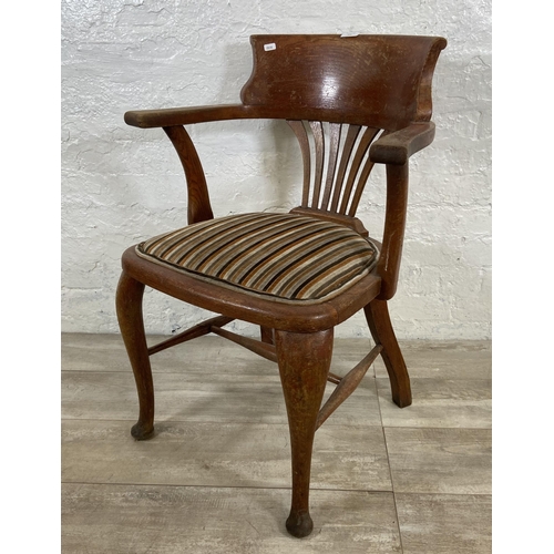 121 - An early 20th century oak desk chair on cabriole supports with lower stretchers and upholstered seat... 