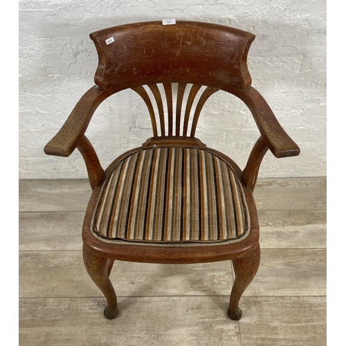 121 - An early 20th century oak desk chair on cabriole supports with lower stretchers and upholstered seat... 