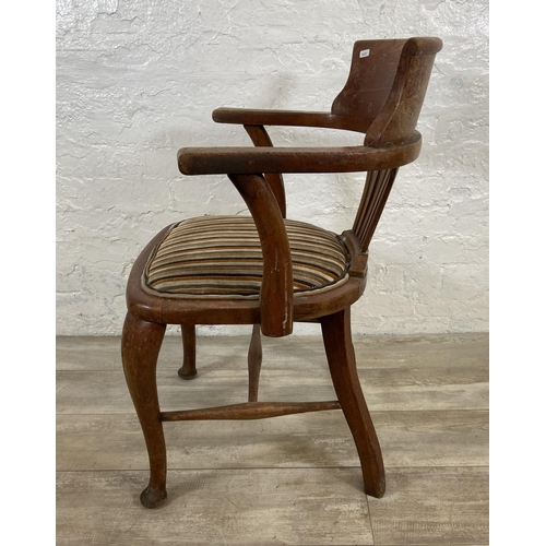 121 - An early 20th century oak desk chair on cabriole supports with lower stretchers and upholstered seat... 