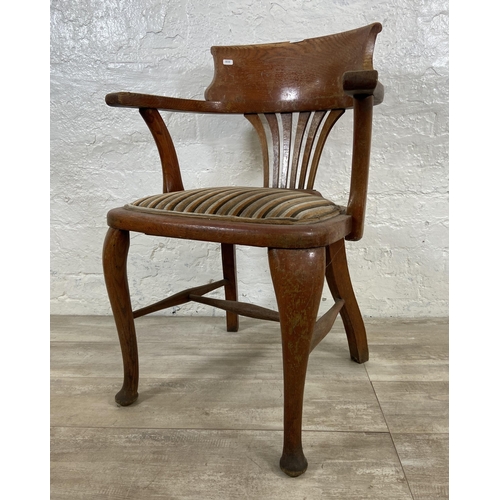 122 - An early 20th century oak desk chair on cabriole supports with lower stretchers and upholstered seat... 