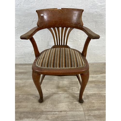 122 - An early 20th century oak desk chair on cabriole supports with lower stretchers and upholstered seat... 