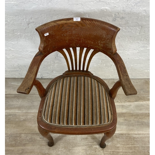 122 - An early 20th century oak desk chair on cabriole supports with lower stretchers and upholstered seat... 