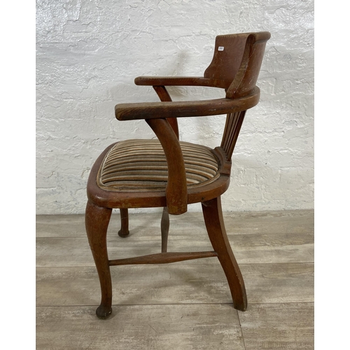 122 - An early 20th century oak desk chair on cabriole supports with lower stretchers and upholstered seat... 