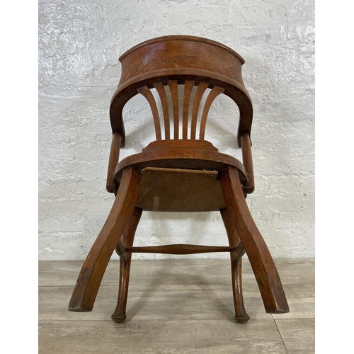 122 - An early 20th century oak desk chair on cabriole supports with lower stretchers and upholstered seat... 