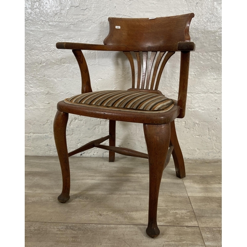 123 - An early 20th century oak desk chair on cabriole supports with lower stretchers and upholstered seat... 